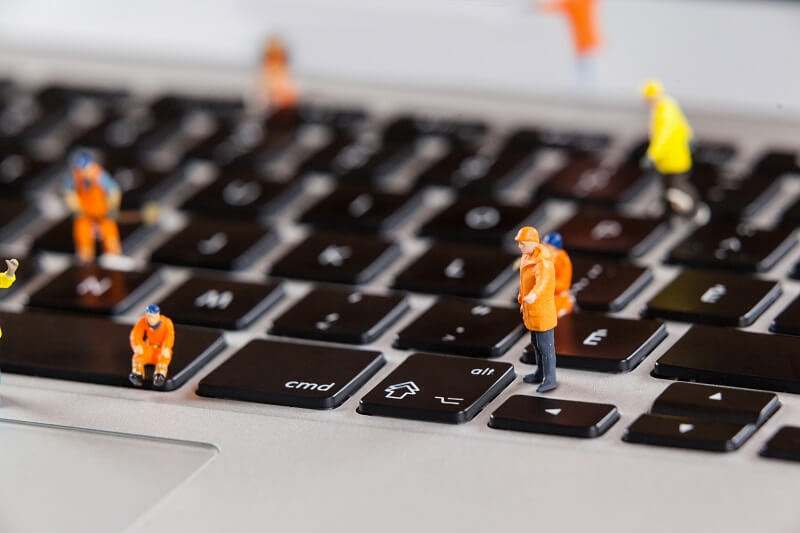 Obrero en teclado de portátil simula trabajar en el mantenimiento de web